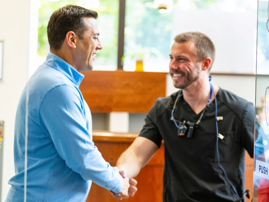 Patient happily shaking hands with Dr. Kyle Polasek after tooth extraction